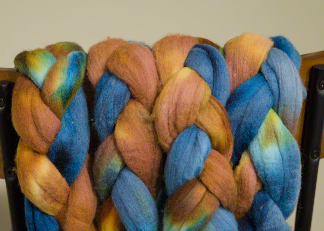 Braided Merino wool top with blue and orange colors on a wooden surface