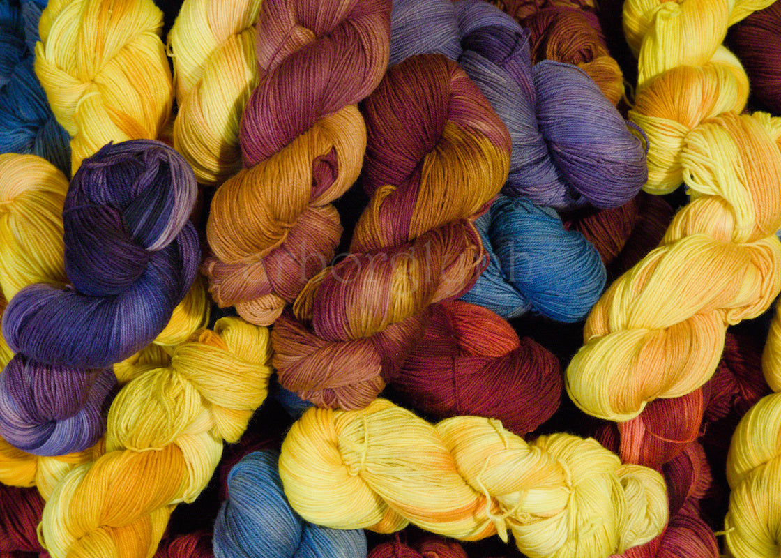 pile of hand dyed merino wool skeins in yellow, blue, purple, red and burgundy