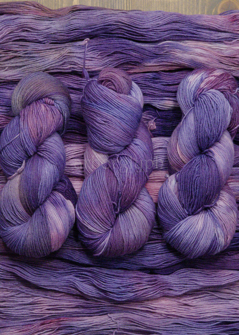 Bundles of purple yarn on a textured surface