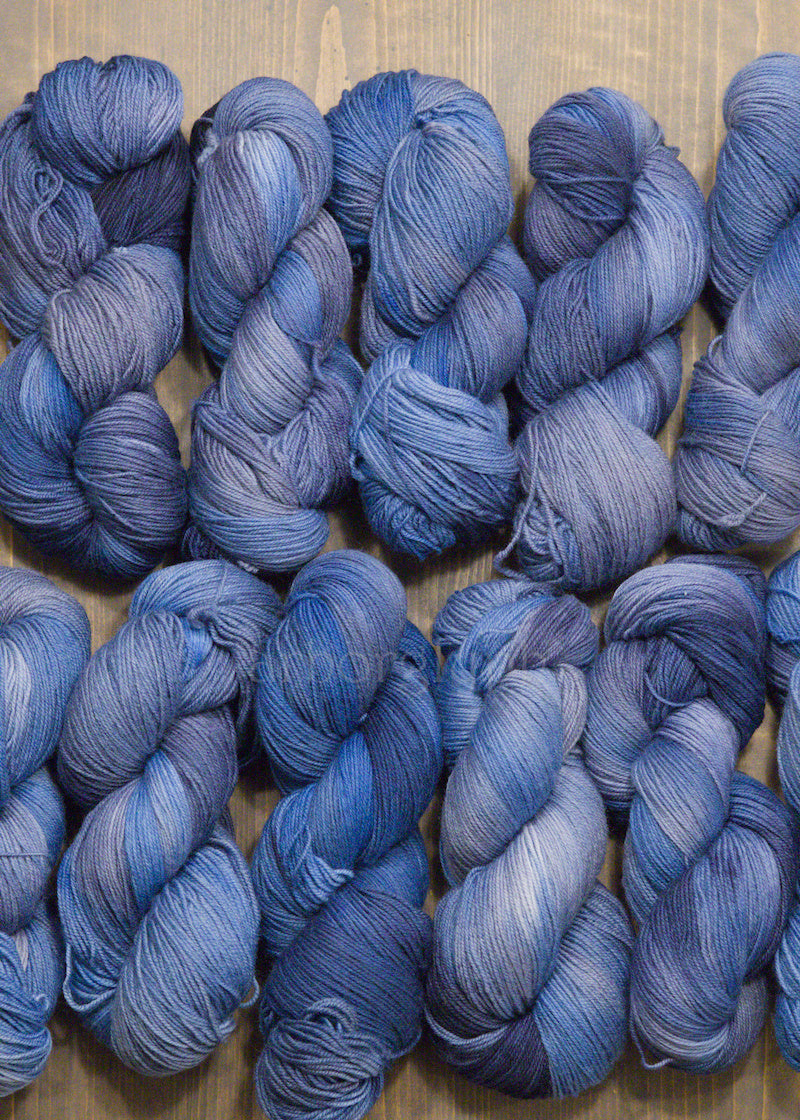 Hand dyed blue Merino yarn skeins on a wooden surface