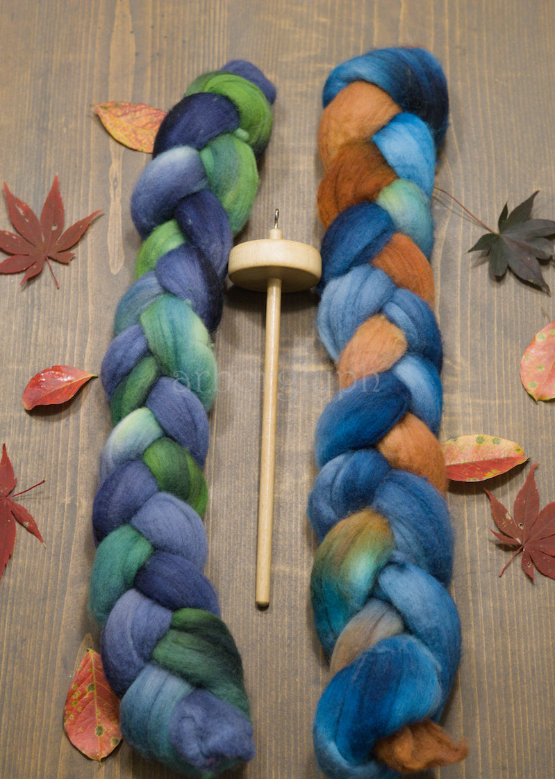 Two braids of combed wool top with a wooden spindle on a wooden surface with autumn leaves.