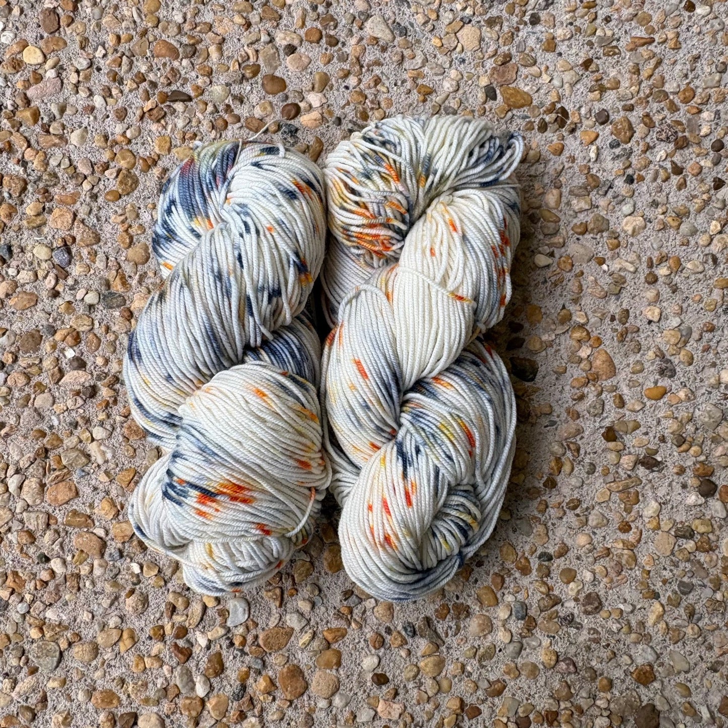 Skein of hand-dyed Cavalier yarn in cream Merino speckled with navy and orange