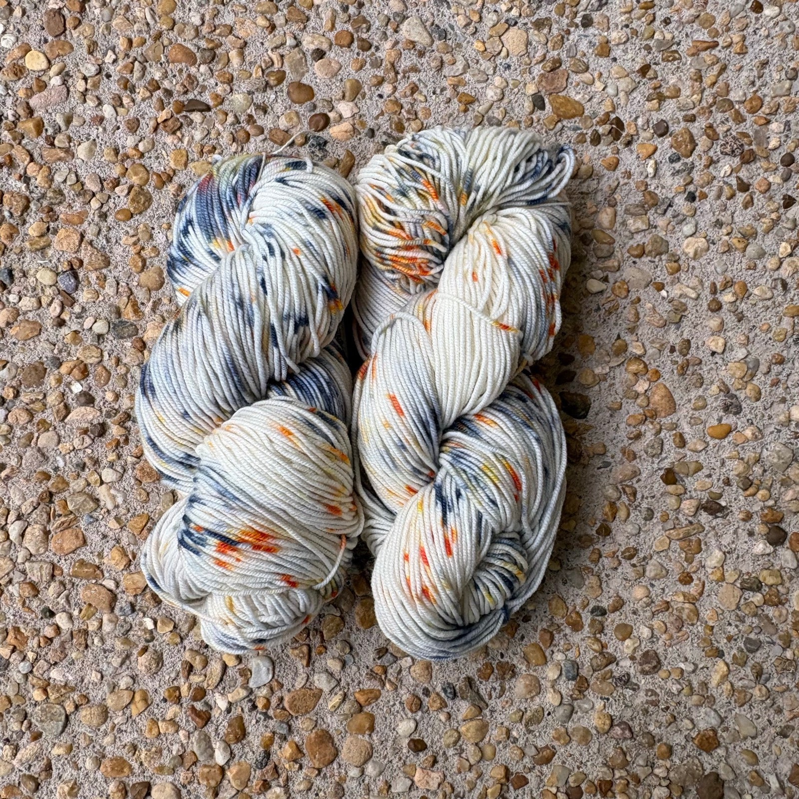 Skein of hand-dyed Cavalier yarn in cream Merino speckled with navy and orange