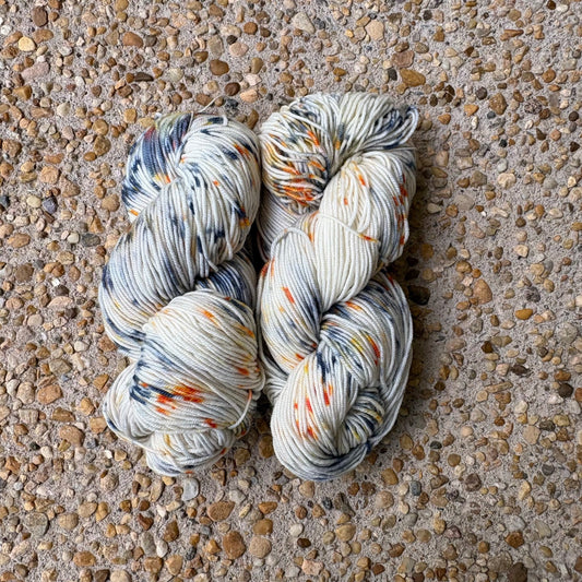Skein of hand-dyed Cavalier yarn in cream Merino speckled with navy and orange