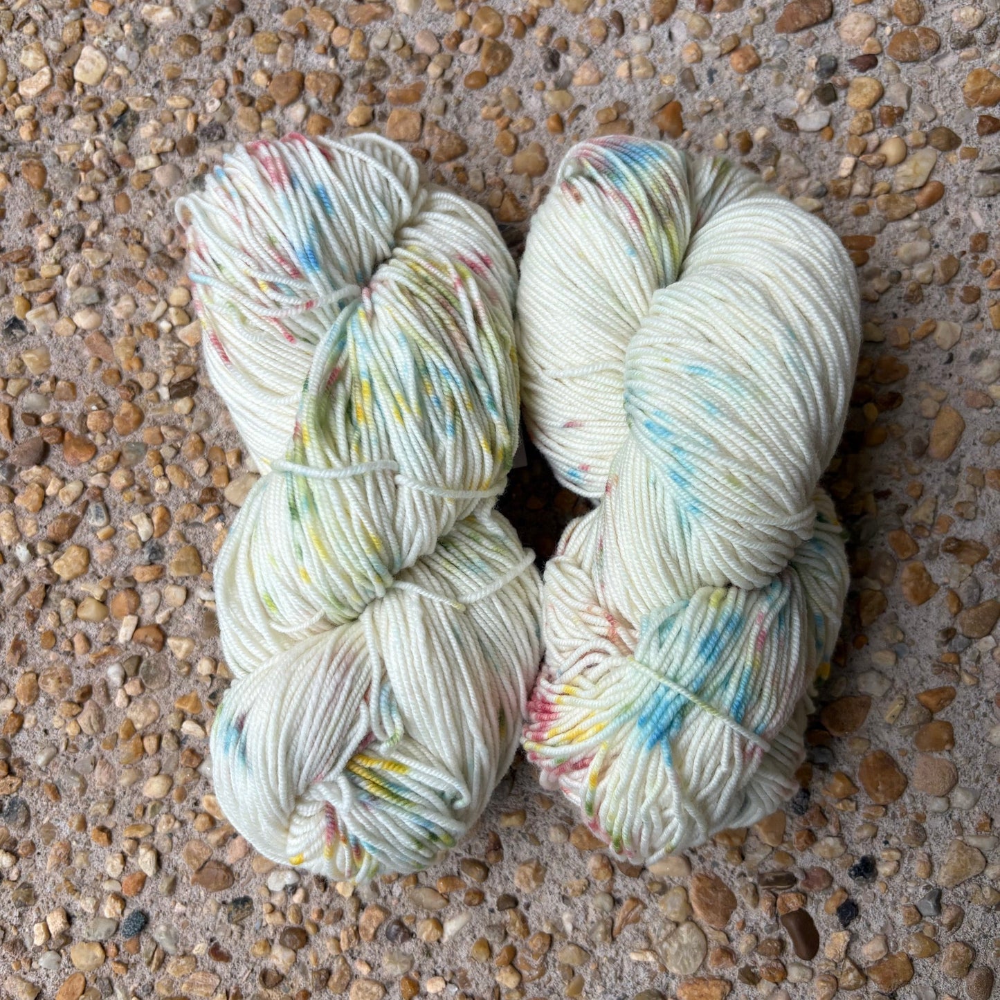 Skein of hand-dyed Confetti yarn in white Merino with pastel rainbow speckles