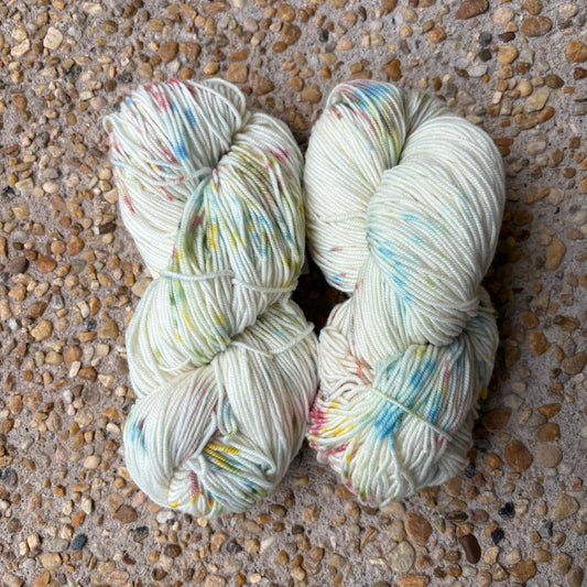Skein of hand-dyed Confetti yarn in white Merino with pastel rainbow speckles