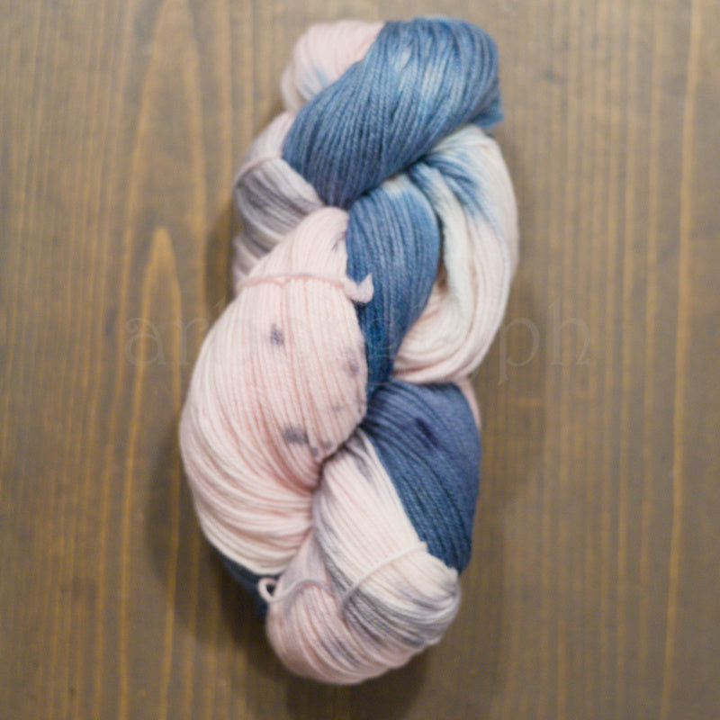Skein of hand-dyed Dawn yarn in variegated blue, pink, and gray Merino