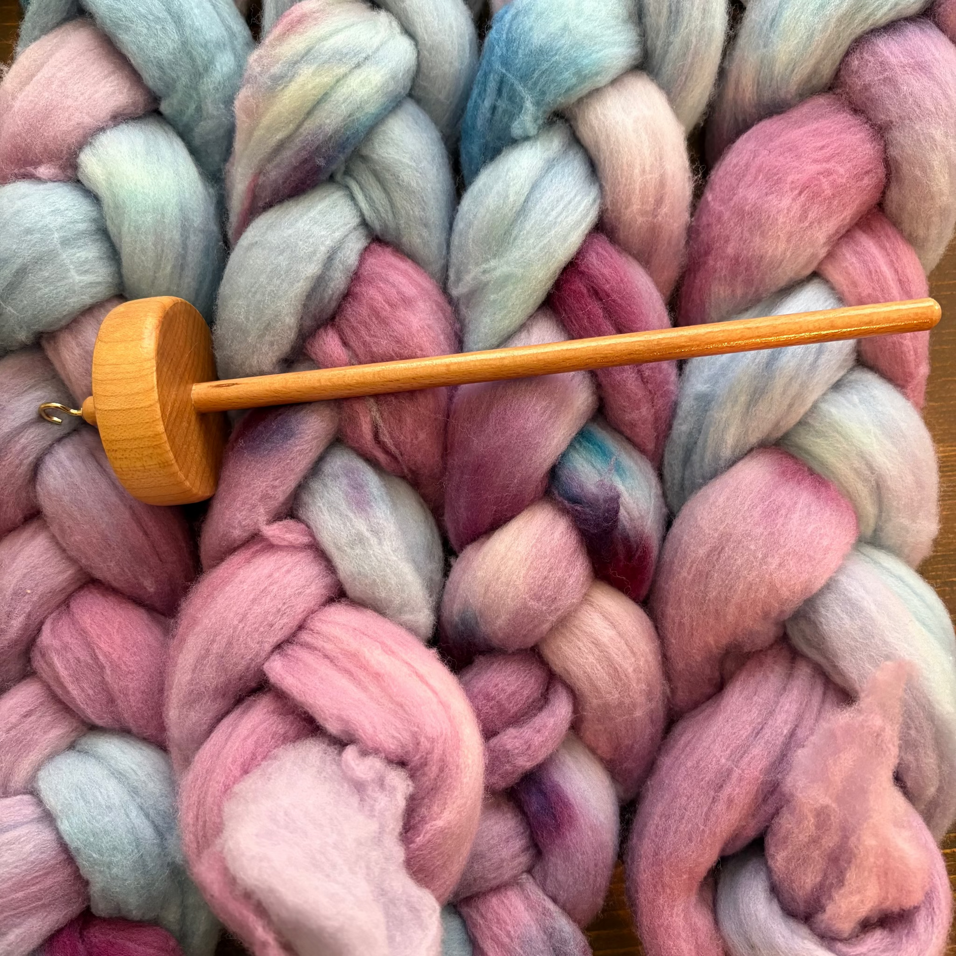 Colorful yarn braid with a wooden drop spindle 