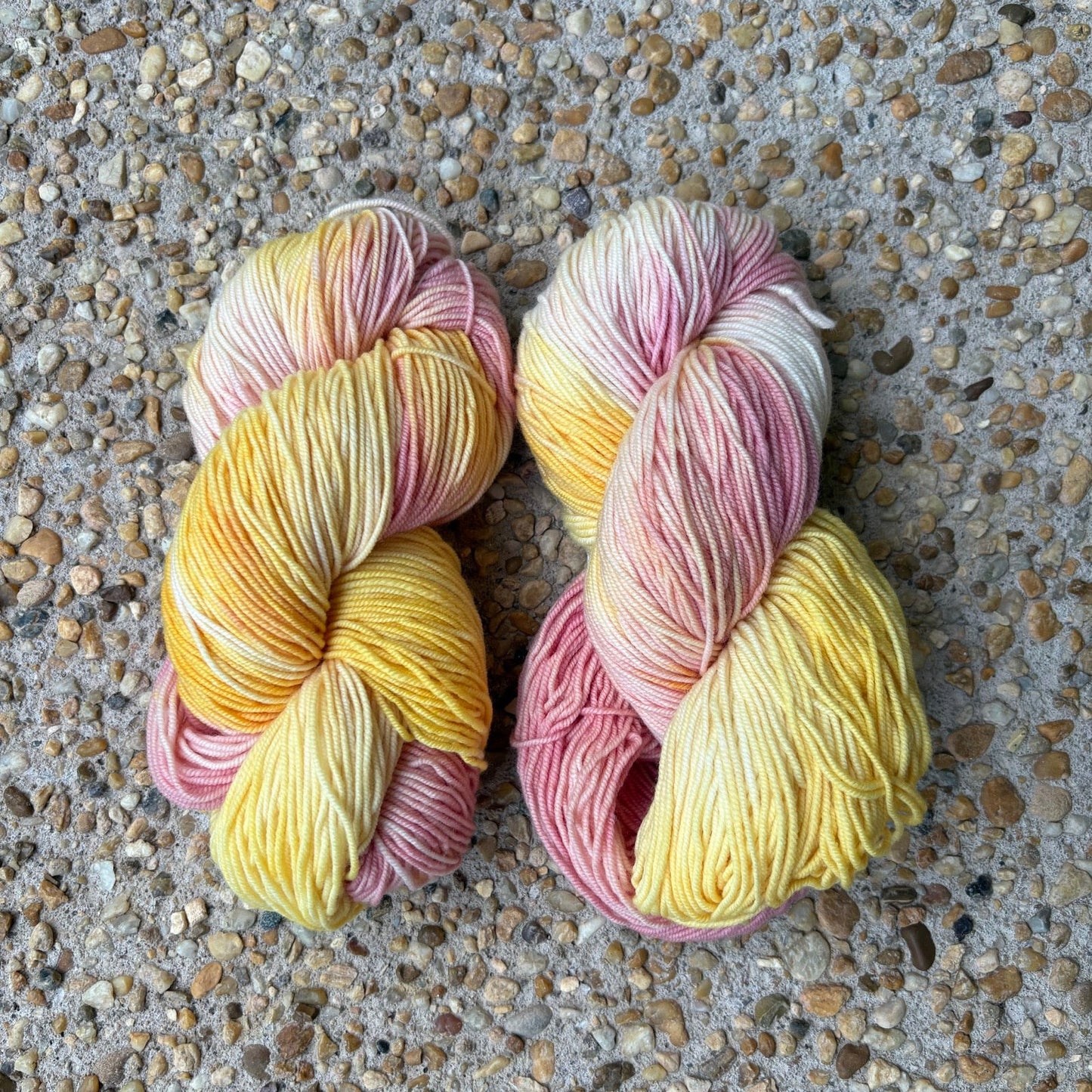 Skein of hand-dyed Peace Rose yarn in variegated buttery yellow and rose pink Merino